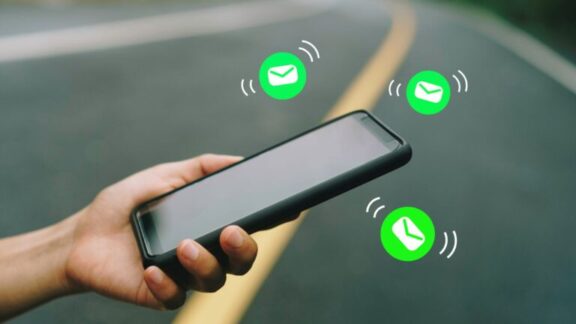 Mano de mujer con smartphone para enviar y recibir SMA sobre fondo de carretera