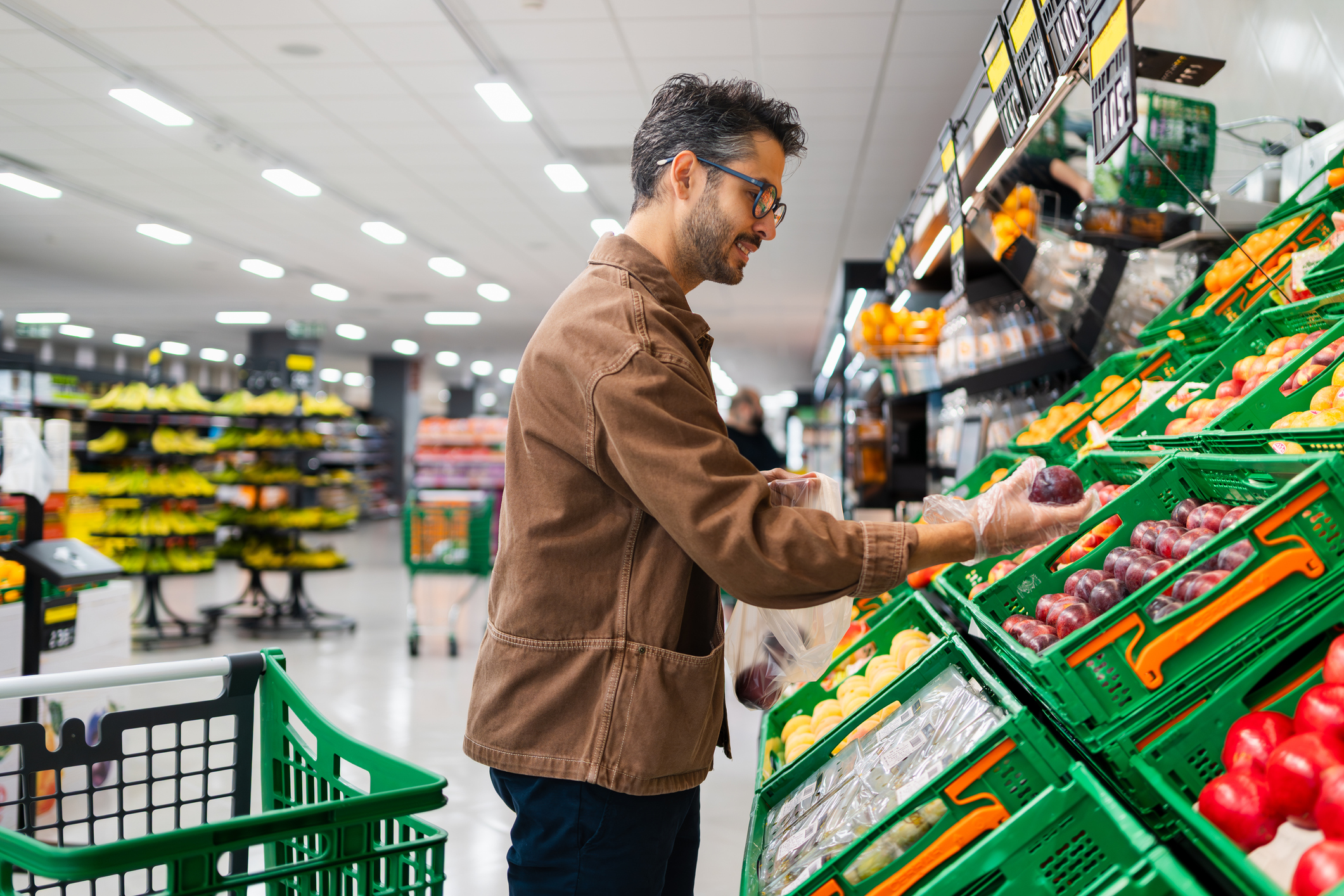 Hombre joven comprando fruta en una franquicia de supermercados