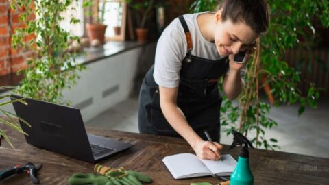 Mujer jardinera apuntando pedido en un cuaderno dentro de su tiendaautónoma anotando pedi