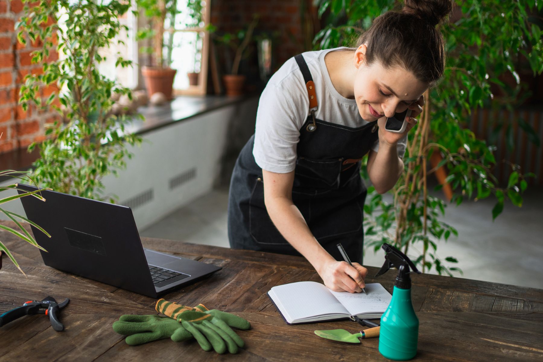 Mujer jardinera apuntando pedido en un cuaderno dentro de su tiendaautónoma anotando pedi