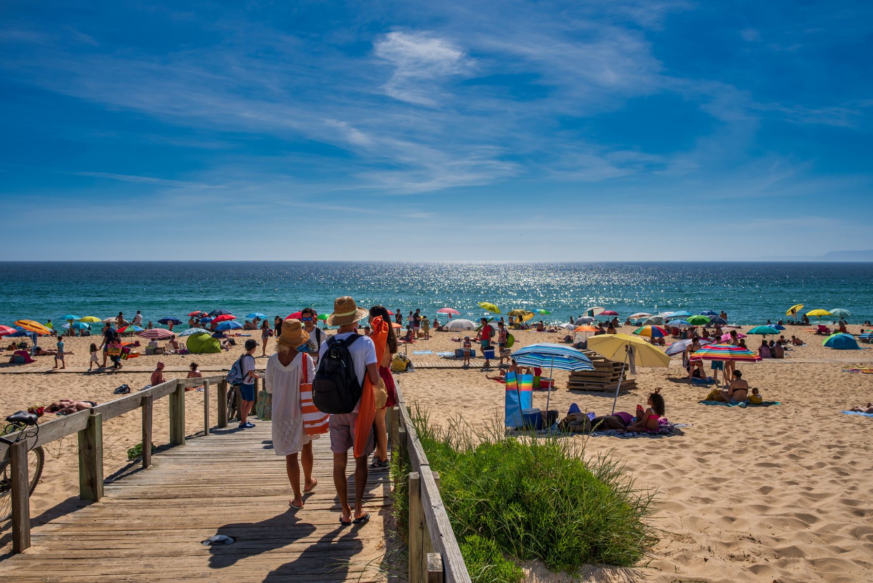 Familia que llega caminando por una pasarela a la playa