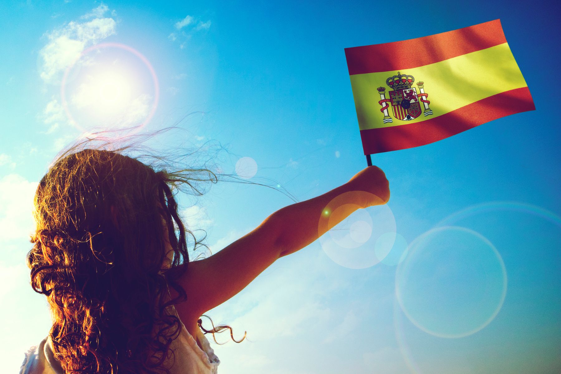 Niña de espaldas ondeando un banderín de España
