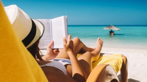 Mujer en hamaca leyendo libro en la playa