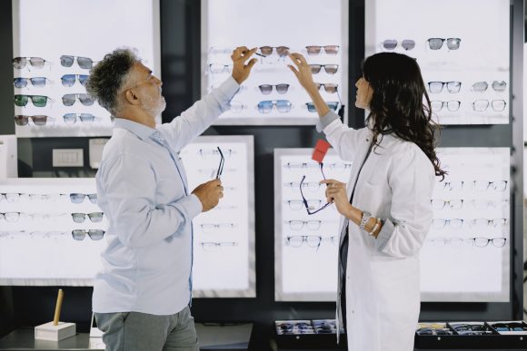 Dependienta en una cadena de ópticas enseñando gafas a un cliente
