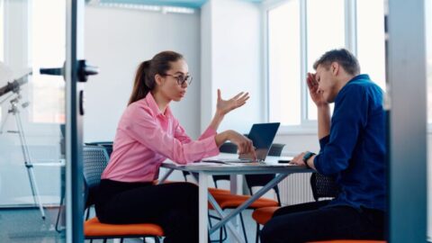 Directora joven corrigiendo y dando indicaciones a un empleado, que se muestra apurado por la conversación