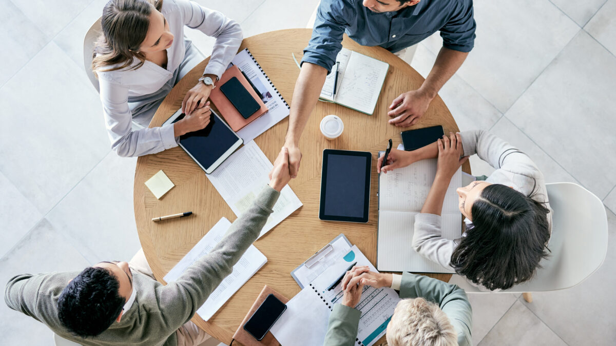 Empresarios estrechándose la mano durante una reunión de equipo en una oficina moderna.