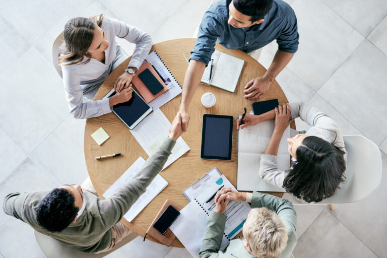 Empresarios estrechándose la mano durante una reunión de equipo en una oficina moderna.