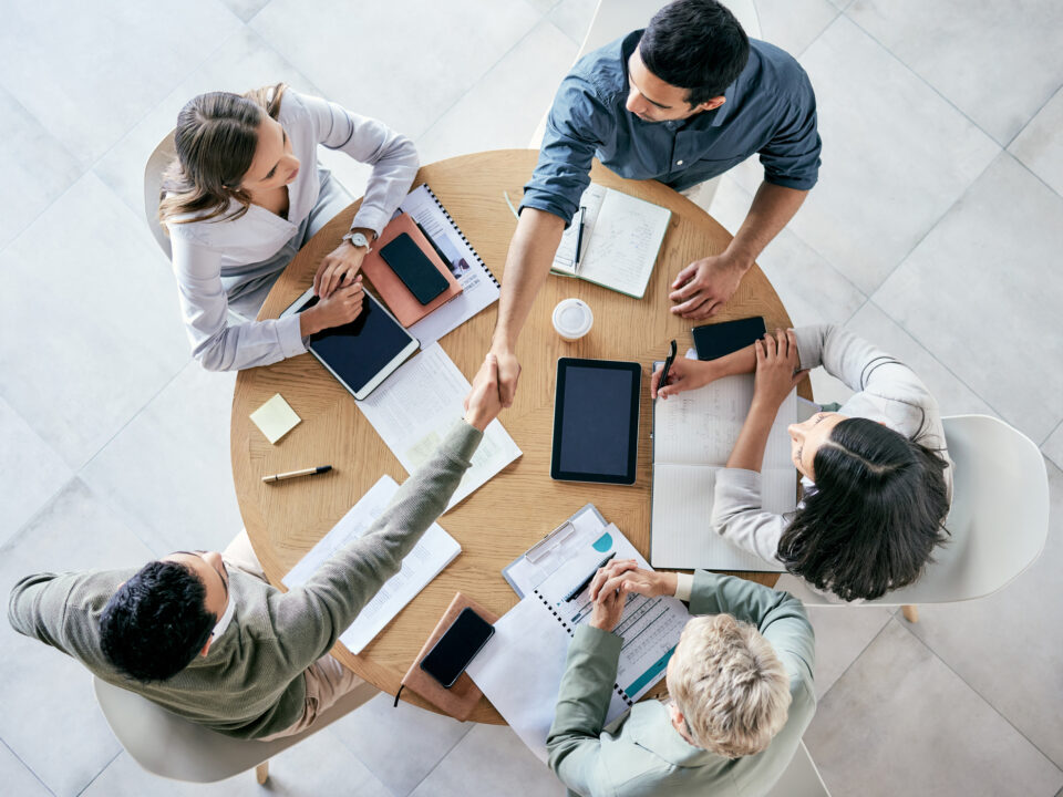 Empresarios estrechándose la mano durante una reunión de equipo en una oficina moderna.