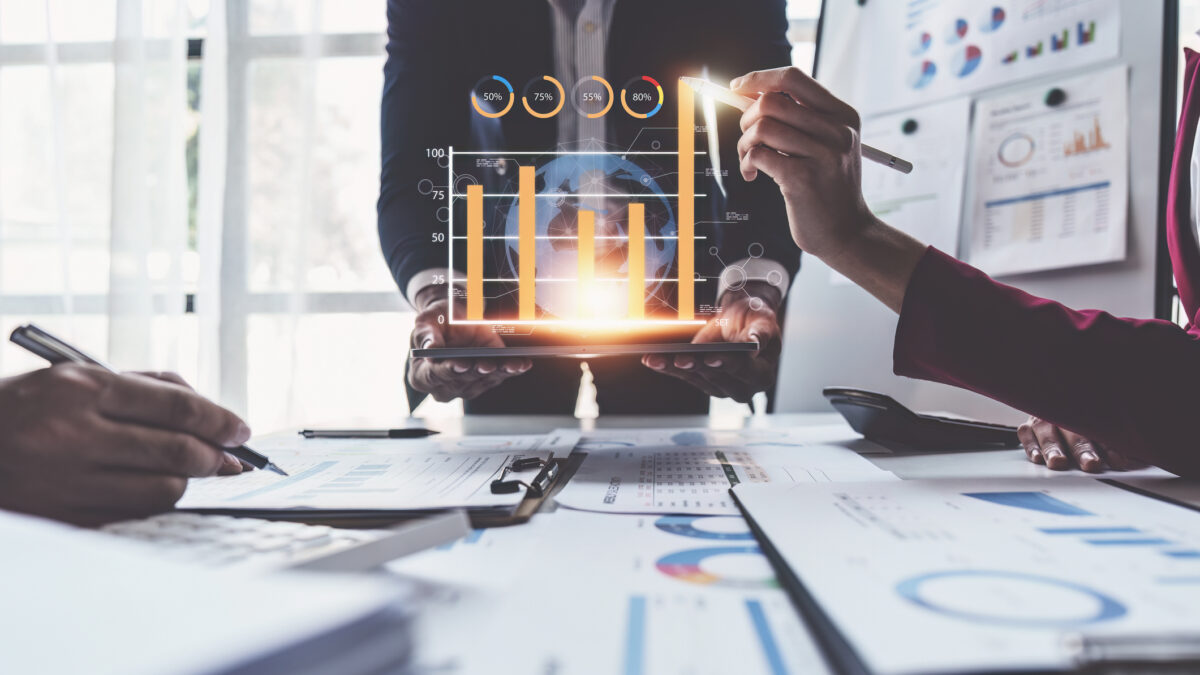 Primer plano de empleados trabajando sobre una mesa con gráficos en papel y gráficos digitales
