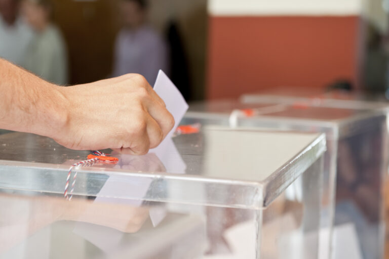 Mano de hombre introduciendo un voto en la urna electoral