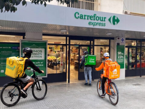 Repartidores en bici esperando fuera de un supermercado Carrefour Express