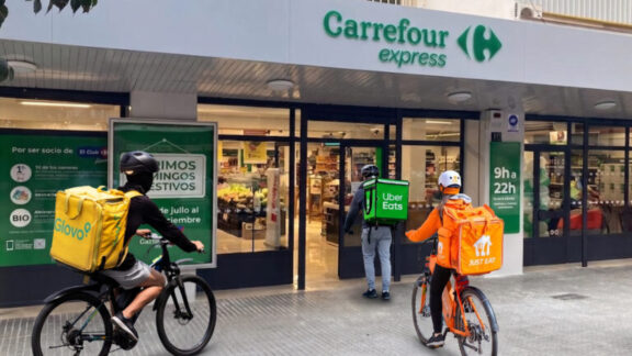 Repartidores en bici esperando fuera de un supermercado Carrefour Express