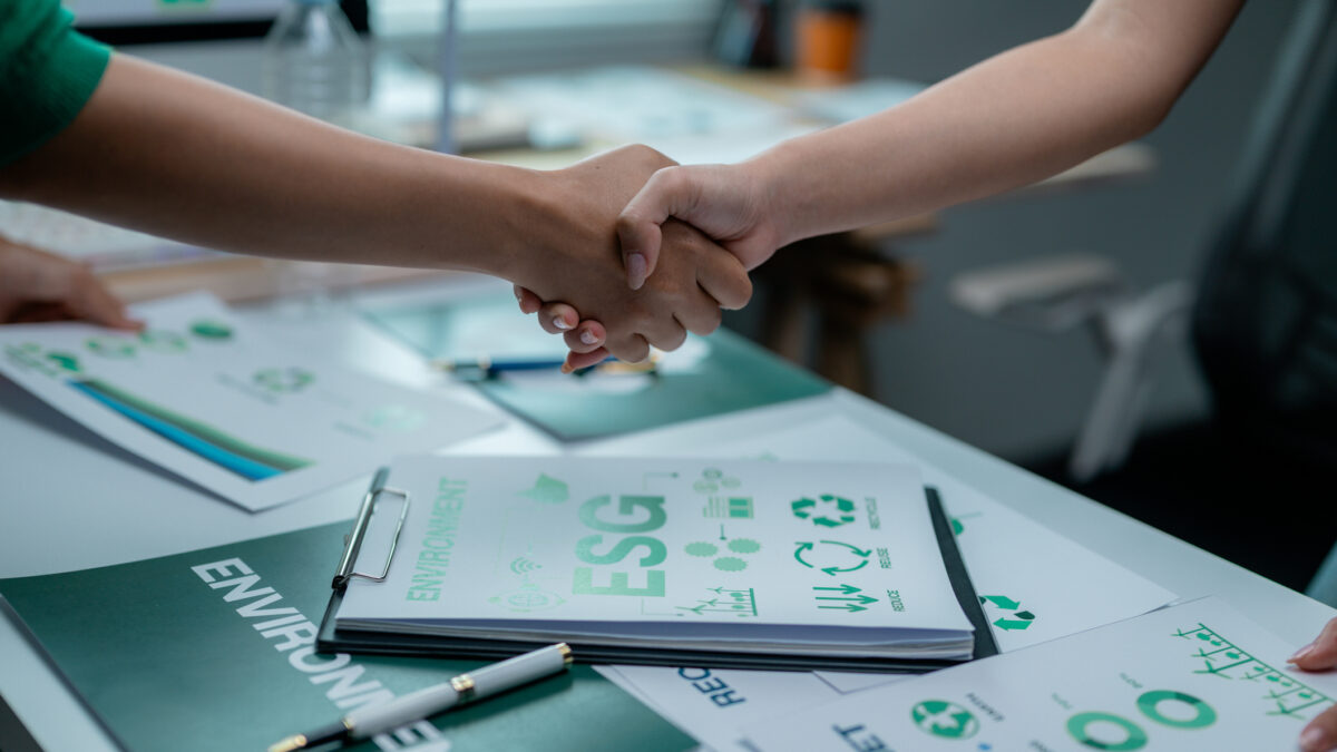 Dos profesionales se dan la mano frente a un documento de ESG