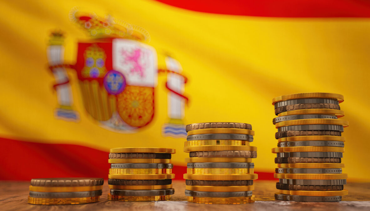 Pilas de monedas de euro sobre el fondo de la bandera de Espana