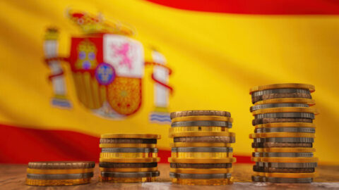 Pilas de monedas de euro sobre el fondo de la bandera de Espana