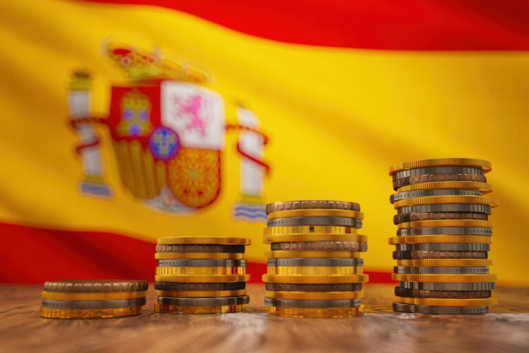 Pilas de monedas de euro sobre el fondo de la bandera de Espana