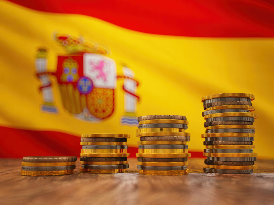 Pilas de monedas de euro sobre el fondo de la bandera de Espana