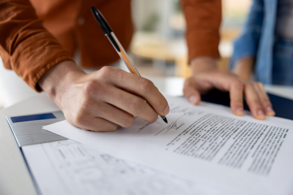 Una persona firma un contrato de alquiler sobre una mesa