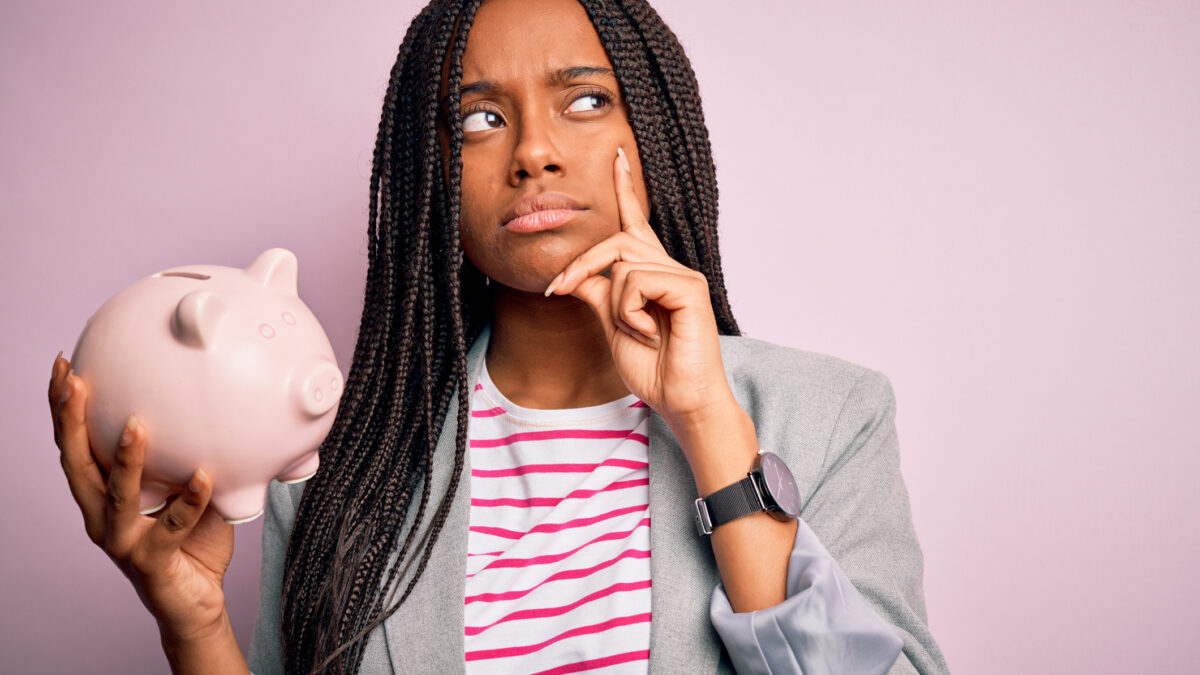 Joven pensativa con una hucha cerdito en la mano. Concepto de ahorro e inversión. Foto: istock