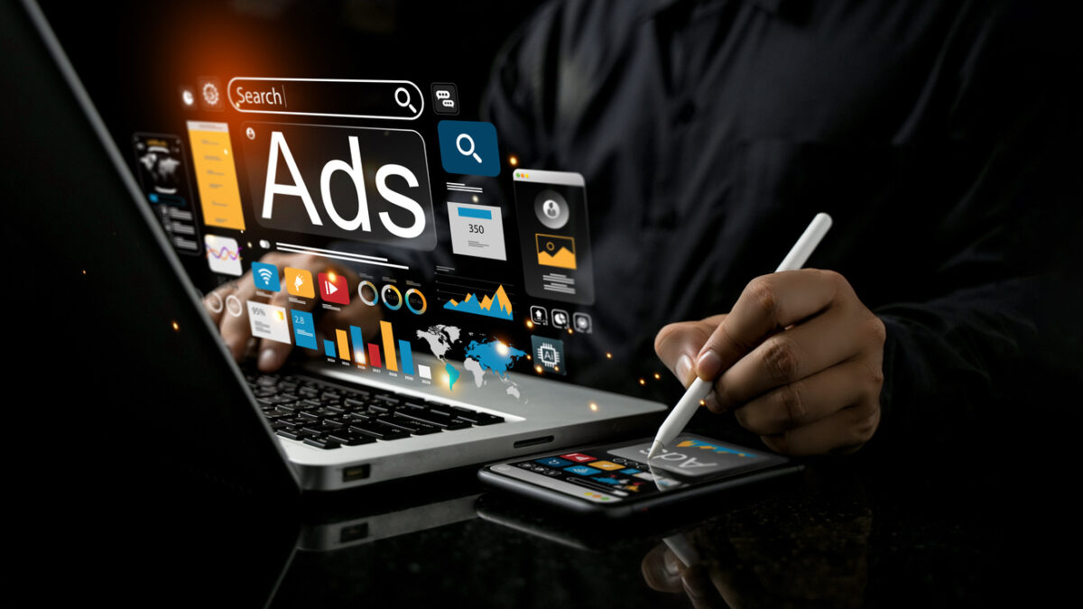 Hombre frente a ordenador y smartphone consultando metricas de publicidad digital