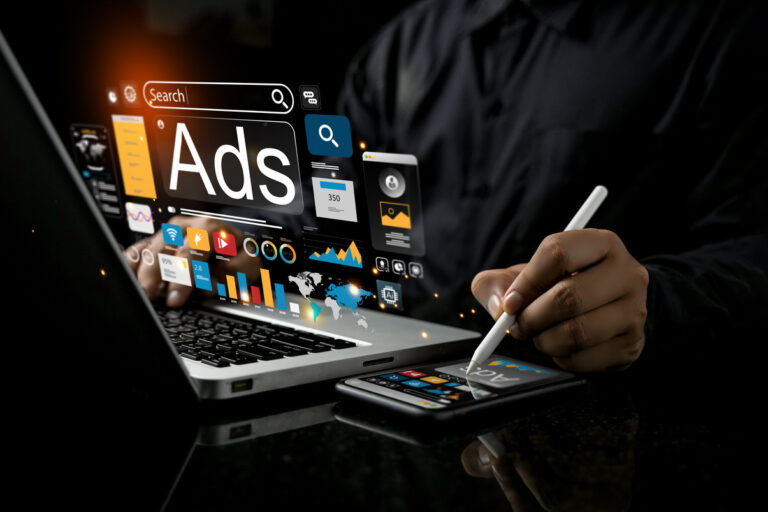 Hombre frente a ordenador y smartphone consultando metricas de publicidad digital