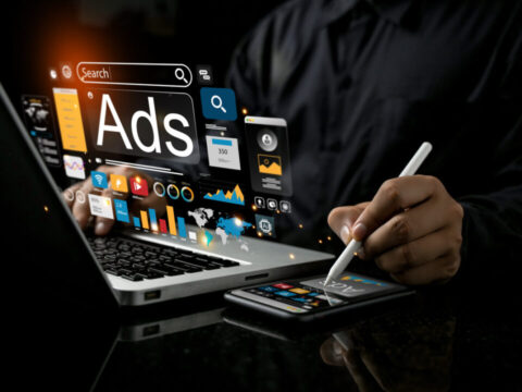 Hombre frente a ordenador y smartphone consultando metricas de publicidad digital