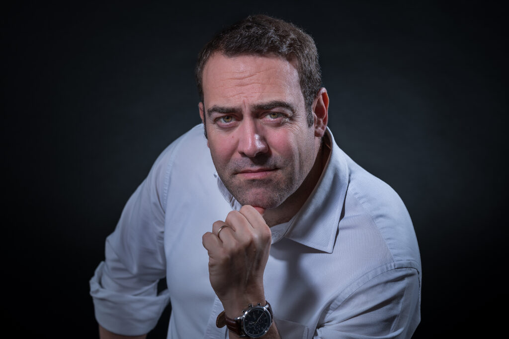 Retrato de Nacho Barraquer, con camisa blanca y la mano apoyada en la barbilla.