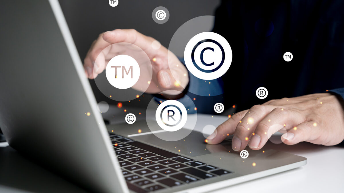Concepto de protección de marca. Hombre tecleando en un portátil y con los símbolos de copyright, registration y trademark