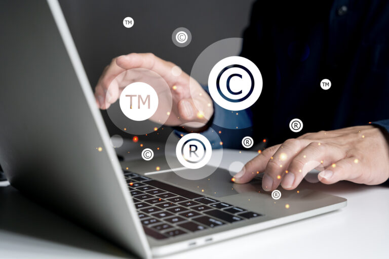 Concepto de protección de marca. Hombre tecleando en un portátil y con los símbolos de copyright, registration y trademark
