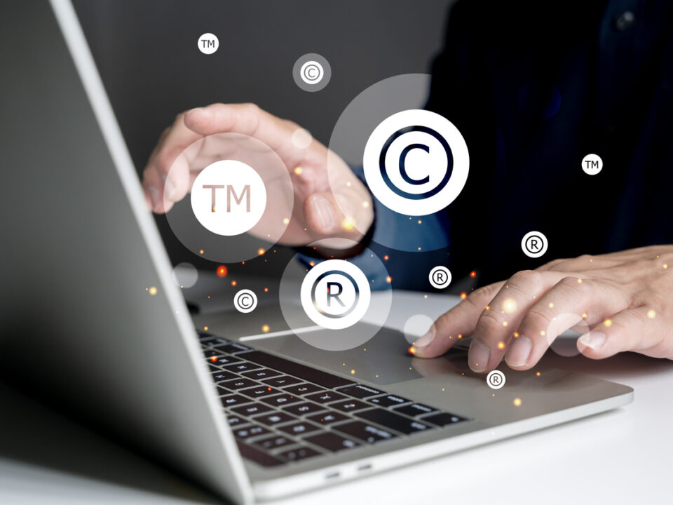 Concepto de protección de marca. Hombre tecleando en un portátil y con los símbolos de copyright, registration y trademark