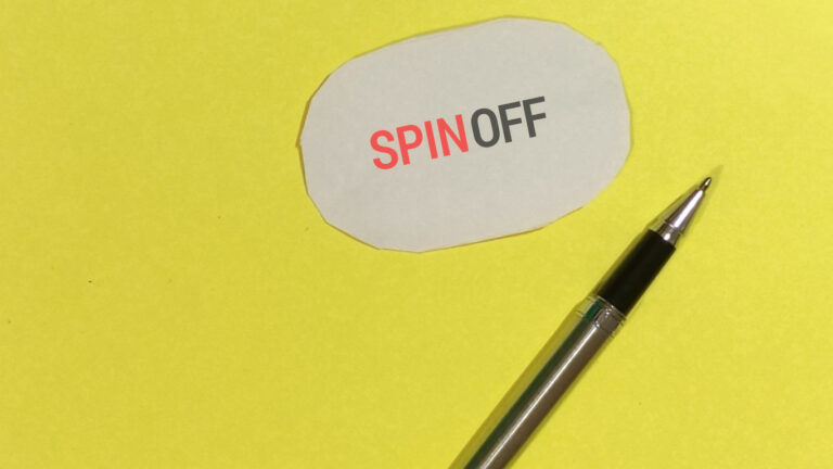 Palabra spin-off sobre fondo amarillo y con un bolígrafo al lado