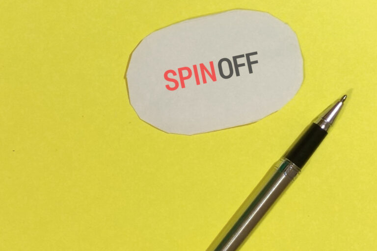 Palabra spin-off sobre fondo amarillo y con un bolígrafo al lado