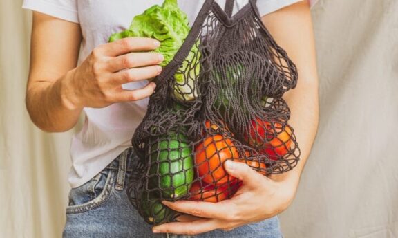 Chica sosteniendo bolsa de tela con verduras