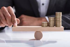 una mano sujetando en equilibrio tres montones de monedas