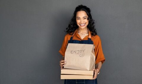 Mujer sonriente con un pedido de comida a domicilio