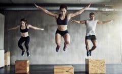 Dos chicas y un chico saltando en un gimnasio