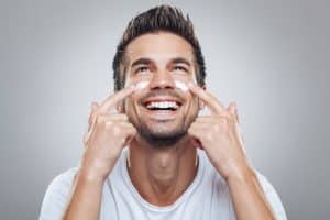 Hombre sonriente echándose crema hidratante