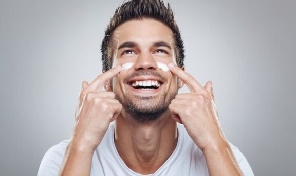 Hombre sonriente echándose crema hidratante