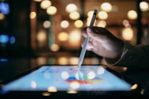 una mano señala con un lapiz sobre una tablet